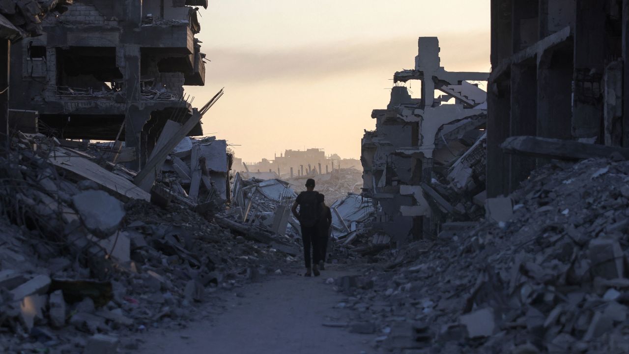 Men walk between piles of rubble in Saftawi neighbourhood, west of Jabalia in the northern Gaza Strip, on August 24, 2025