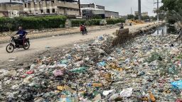 People ride past a drain clogged with plastic waste, disposed along a roadside in Karachi on August 24, 2025. Floodwater gushing through mountain villages, cities rendered swamps -- as Pakistan's monsoon season once again delivers scenes of calamity it also lays bare woeful preparedness. Since it began in June, this year's monsoon has killed around 800 people and damaged more than 7,000 homes, with further downpours expected through September. (Photo by Asif HASSAN / AFP) / To go with 'Pakistan-Environment-Climate-Monsoon-Infrastructure', FOCUS (Photo by ASIF HASSAN/AFP via Getty Images)          
