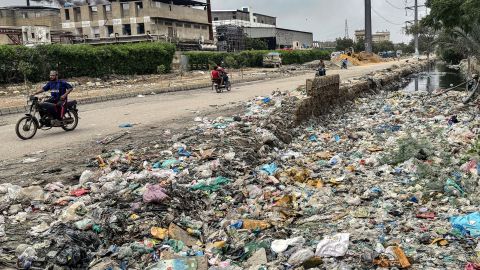 People ride past a drain clogged with plastic waste, disposed along a roadside in Karachi on August 24, 2025. Floodwater gushing through mountain villages, cities rendered swamps -- as Pakistan's monsoon season once again delivers scenes of calamity it also lays bare woeful preparedness. Since it began in June, this year's monsoon has killed around 800 people and damaged more than 7,000 homes, with further downpours expected through September. (Photo by Asif HASSAN / AFP) / To go with 'Pakistan-Environment-Climate-Monsoon-Infrastructure', FOCUS (Photo by ASIF HASSAN/AFP via Getty Images)