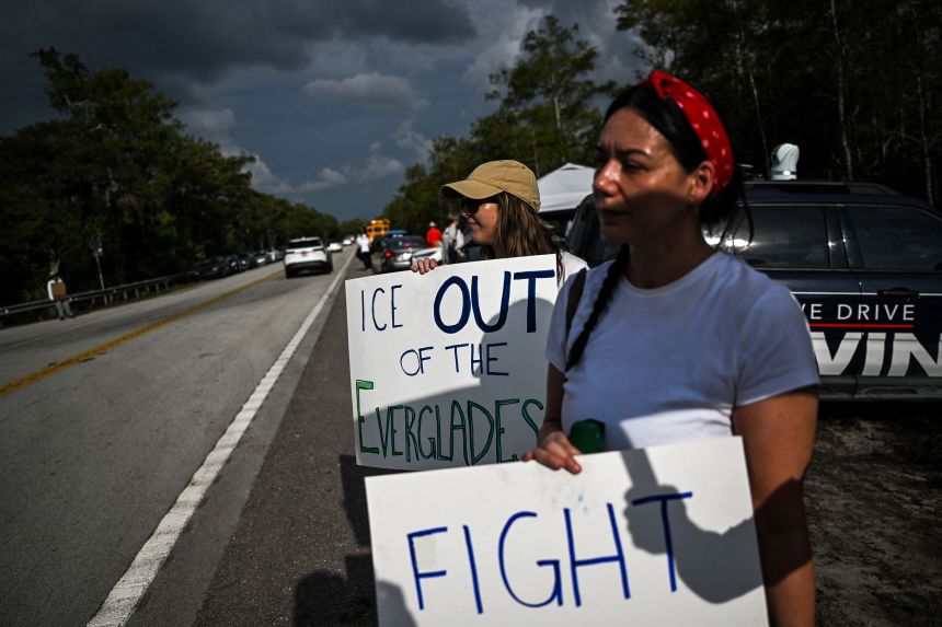 Members of "Leaders of Faith and Conscience" hold posters  as they attend a weekly interfaith vigil outside "Alligator Alcatraz."