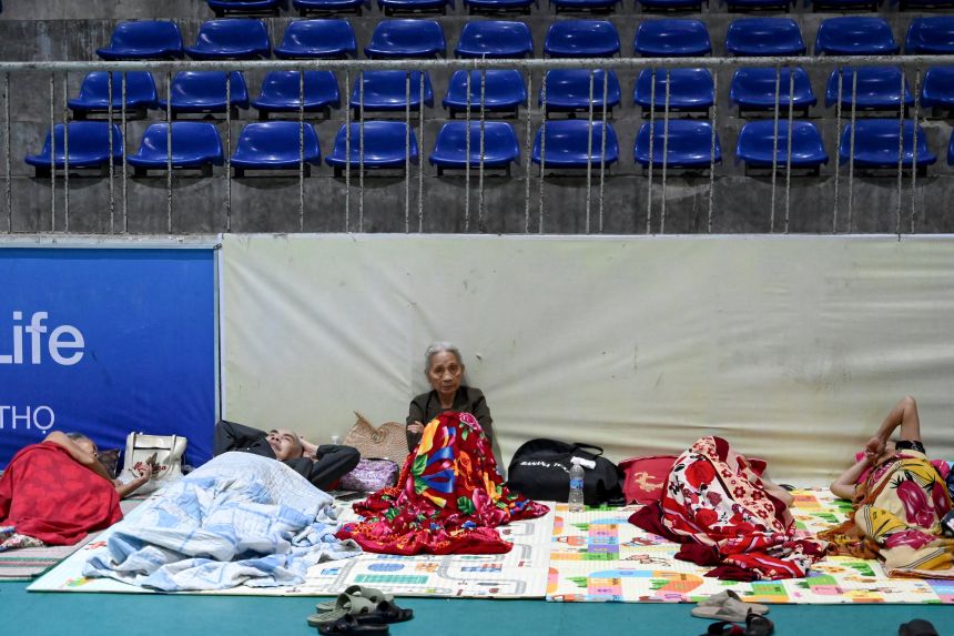 People take shelter inside the Nghe An Provincial Gymnasium in Vinh city, Nghe An province on August 25, 2025, before Typhoon Kajiki makes landfall in Vietnam.