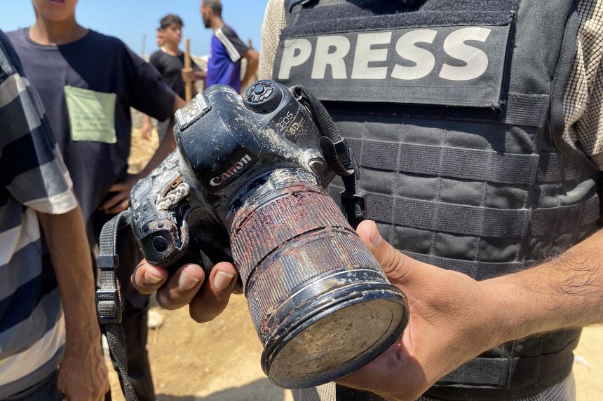 A journalist holds the blood-covered camera belonging to Palestinian photojournalist Mariam Dagga, a journalist who freelanced for AP since the start of the war and who was killed in an Israeli strike on Nasser hospital in Khan Younis in the southern Gaza Strip, during her funeral on August 25, 2025.
