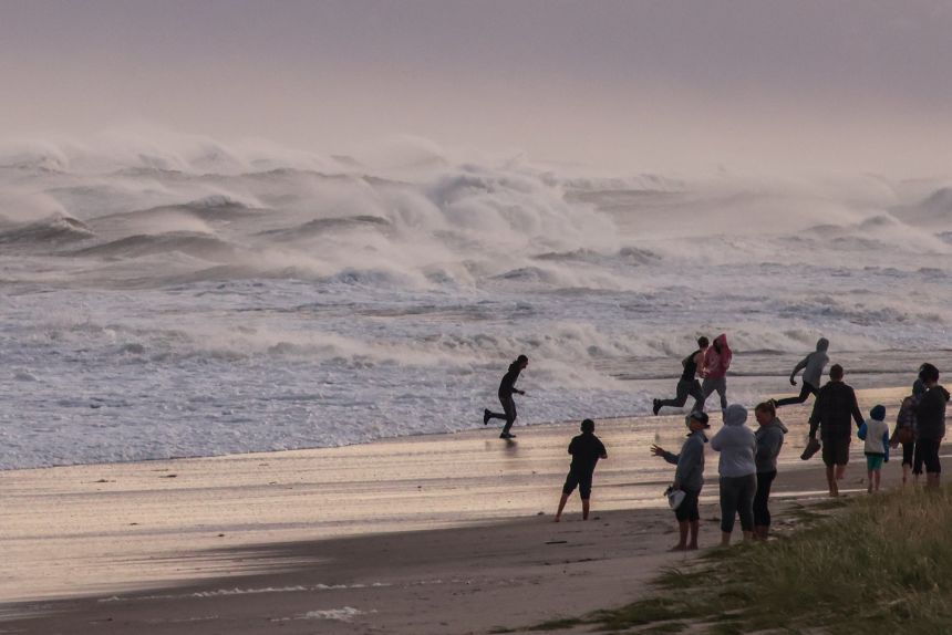 People run from the waves on Smith Point Beach in Shirley, New York, as Hurricane Erin churns up the eastern seaboard on August 21, 2025.