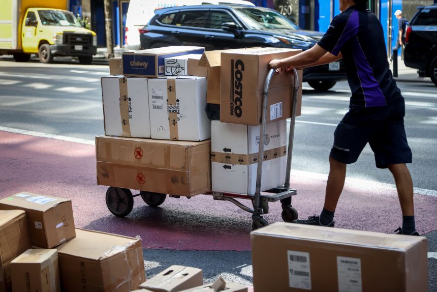 A delivery worker pushes a cart of packages.