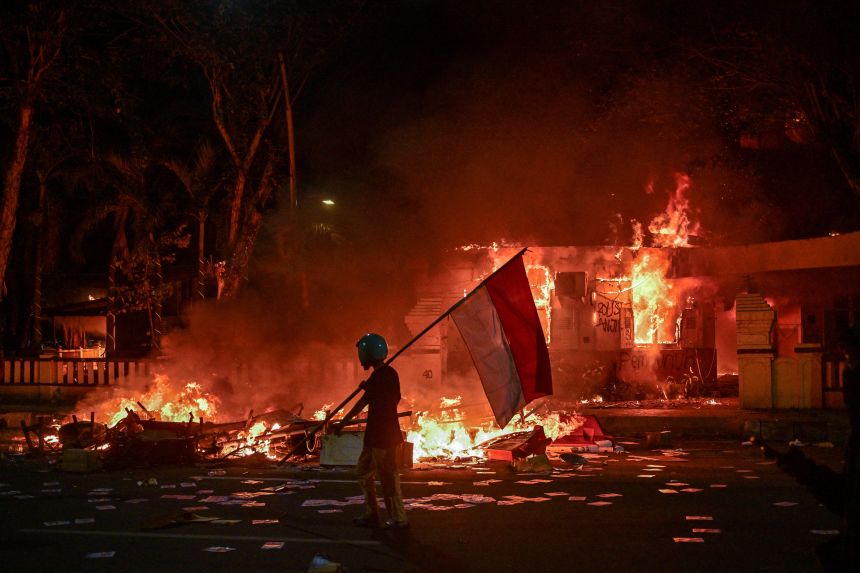 Protesters will walk with Indonesian flags in front of the police headquarters that was lit and sacked during a demonstration in Surabaya on August 31, 2025.
