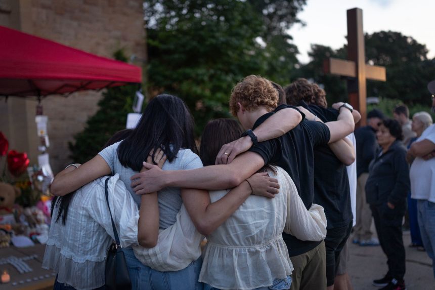 People gather at a memorial for victims of the shooting at Annunciation Catholic Church on Thursday.