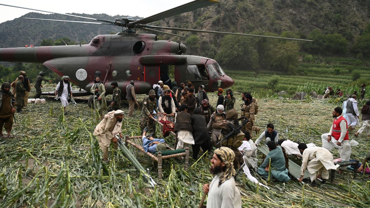 Afghan volunteers and Taliban security personnel work to move injured people near a military helicopter following earthquakes in the Mazar Dara village of Nurgal, a district of the Kunar Province, in Eastern Afghanistan, on September 1, 2025.