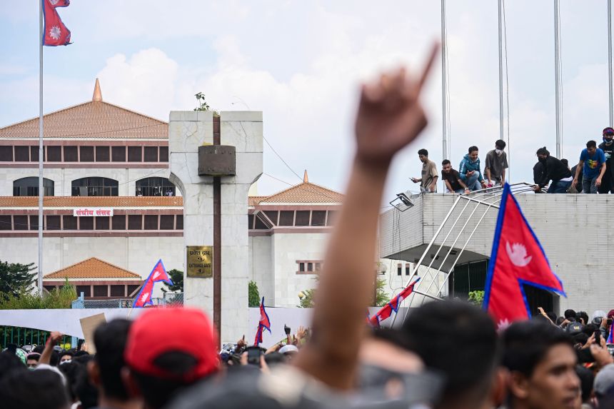 Gen Z protesters gather on the roof and in front of the parliament house on Monday as clashes erupt with police at the Federal Parliament in Kathmandu.