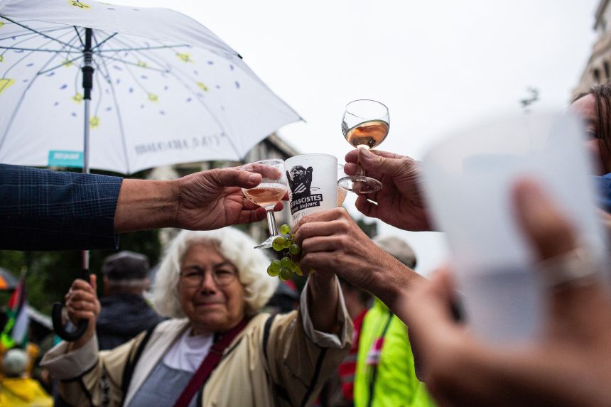 Demonstrators raise their glasses at a "Bayrou’s farewell party" protest on Monday, in Clermont-Ferrand, France, ahead of the confidence vote that ousted the prime minister.