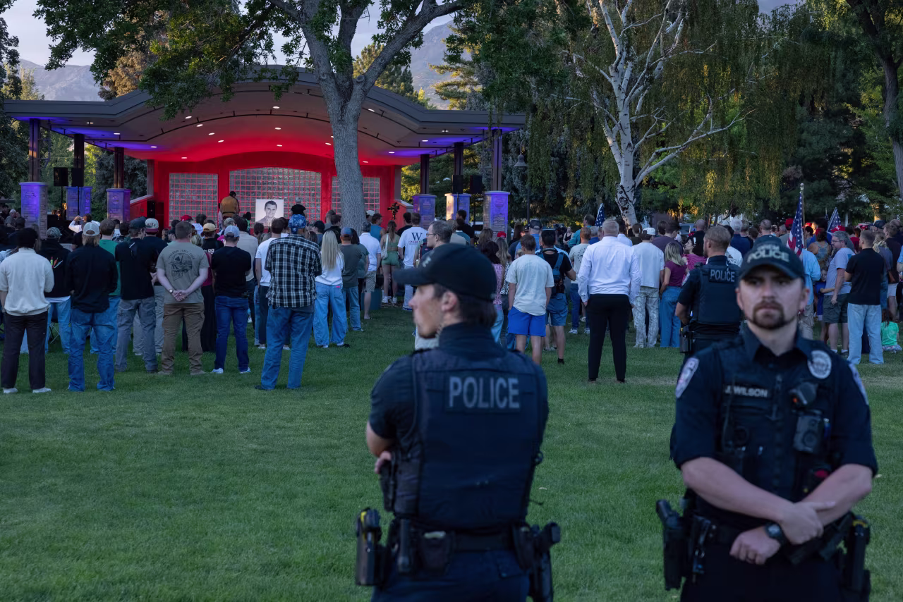 Police officers stand guard as people pay their respects during a candlelight vigil for youth activist and influencer Charlie Kirk at a makeshift memorial at Orem City Center Park in Utah on Thursday.