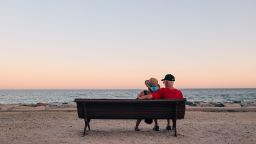 A couple enjoys the tranquility of the sunset, sitting on a bench facing the Mediterranean Sea, in Torremolinos, Spain.