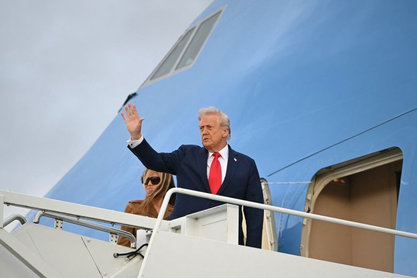 President Donald Trump gestures as he and First Lady Melania Trump board Air Force One at Stansted Airport, in Stansted, north of London, on Thursday.