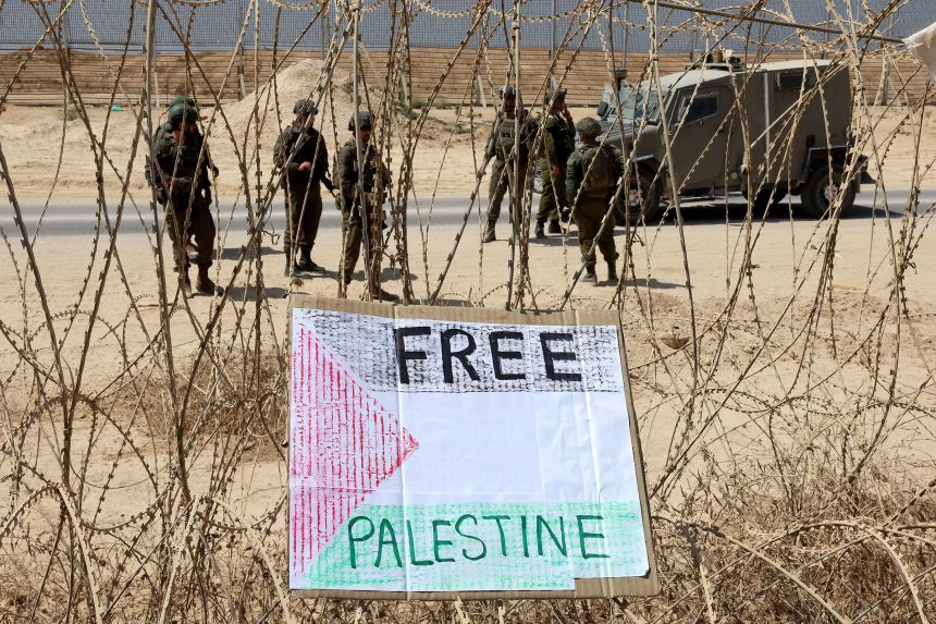 A sign placed by left-wing Israeli activists hangs along the southern Israeli border with the Gaza Strip on Friday, following a protest calling for an end to the war between Israel and Hamas.