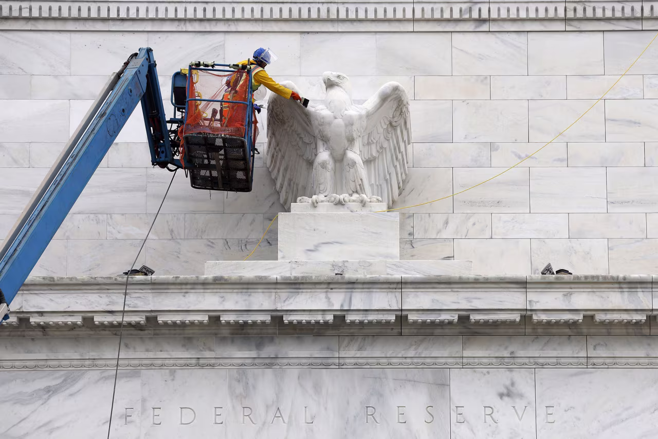 Workers clean and paint an eagle statue on the Marriner S. Eccles Federal Reserve Board Building, the main offices of the Board of Governors of the Federal Reserve System on September 16 in Washington, DC.