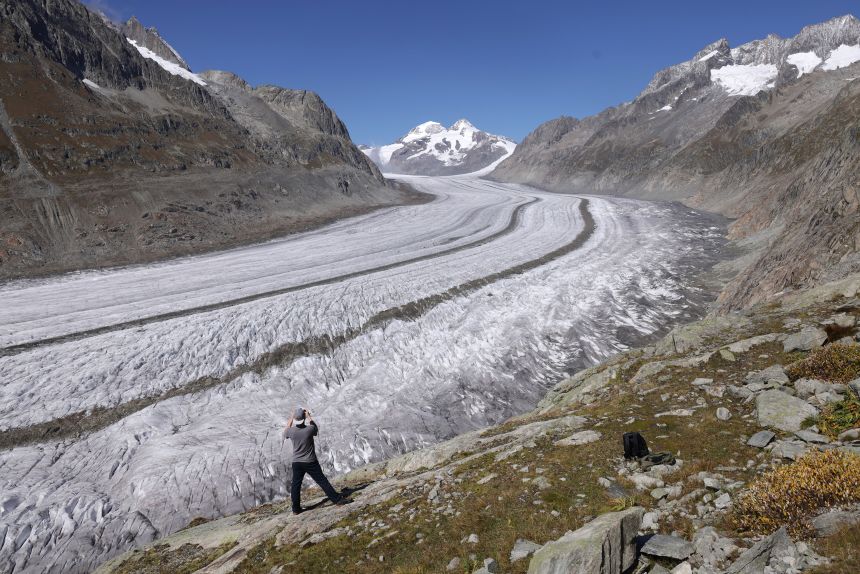A hiker looks out at the Aletsch Glacier - Switzerland's biggest glacier - on September 14, 2025 near Bettmeralp. Scientists from Glacier Monitoring in Switzerland (GLAMOS) have recorded 4.6 meters in diminished vertical thickness since last year at the glacier's upper section.