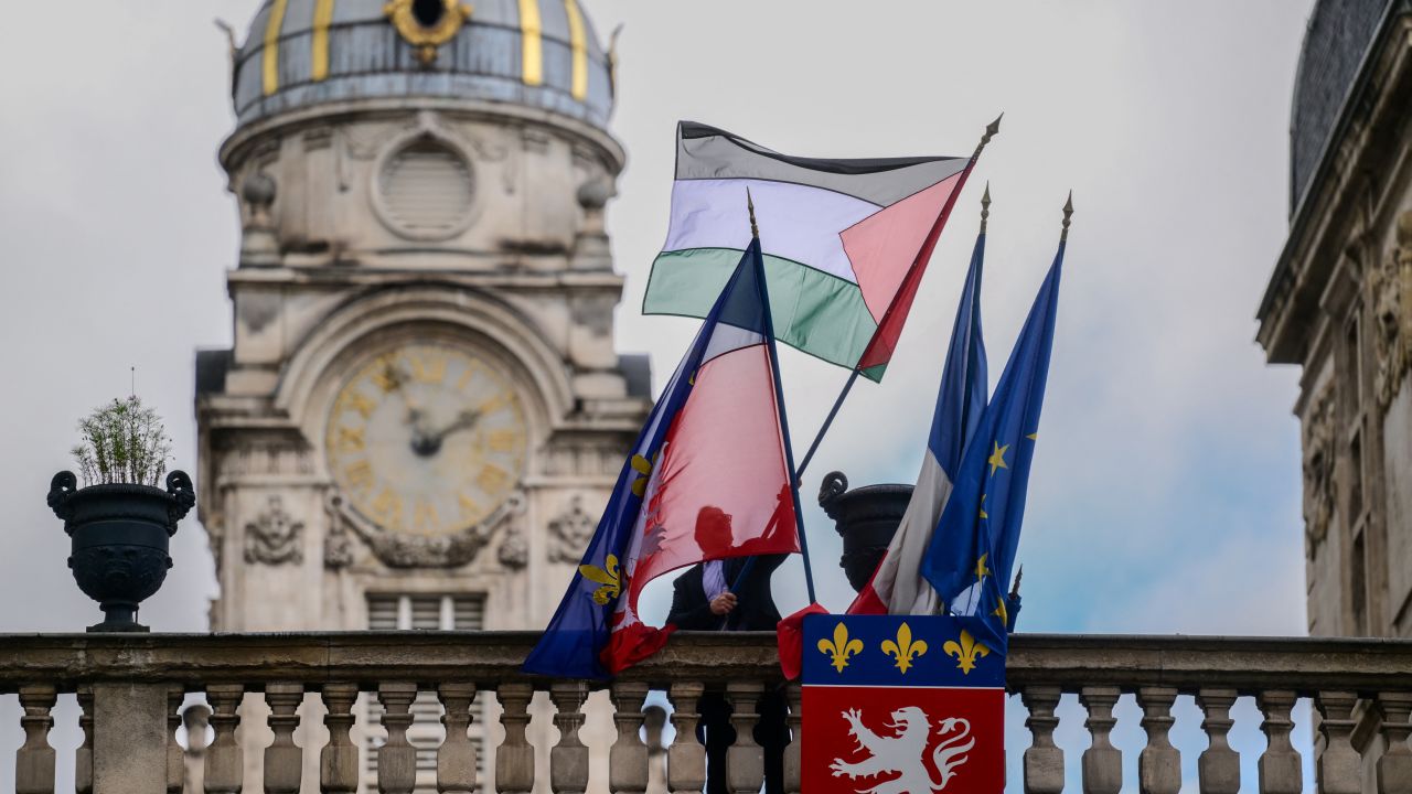 An employee places the Palestinian flag along side the French Flag, the flag of Lyon, and the European Union flag, over the entrance of the Lyon City Hall, in eastern France, on the day France plans the recognition of a Palestinian State at the United Nations on September 22. Over 50 town halls in France were flying the Palestinian flag on September 22, 2025, in defiance of an interior ministry warning not to do so ahead of the recognition of a Palestinian state by French President Emmanuel Macron.
