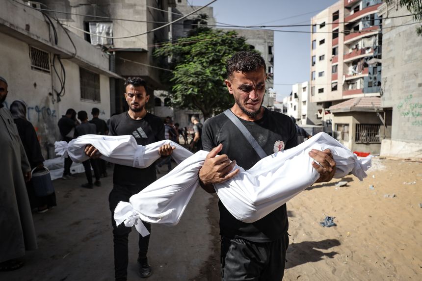 The bodies of Palestinians who were killed by an Israeli attack in Al-Shati Refugee Camp, Gaza City, are carried on Tuesday. The military invasion has forced tens of thousands of people to flee.