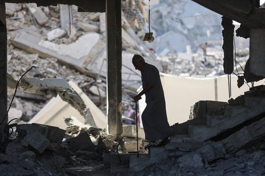 An elderly man walks amid the rubble of a building as Palestinians displaced by the conflict take shelter at the Qatari-built Hamad City residential complex in northwestern Khan Yunis, in the southern Gaza Strip, on September 24, 2025.
