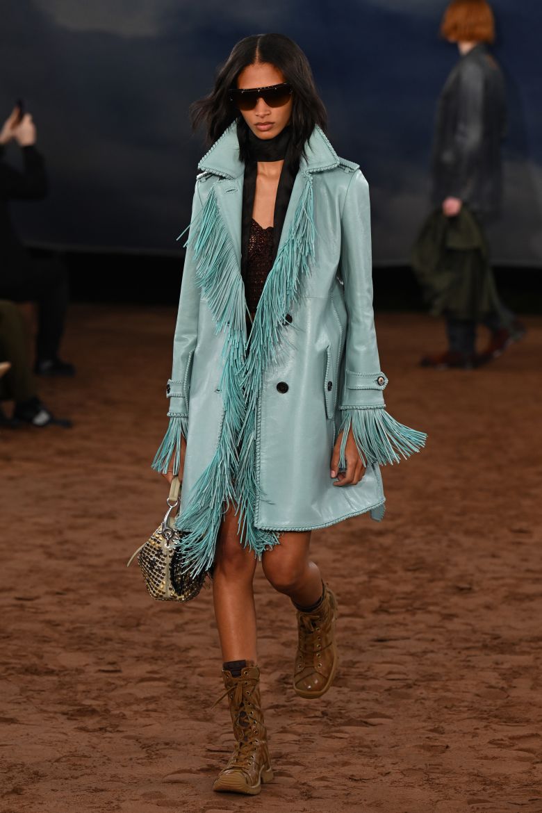 A model walks the runway in a festival-worthy fringed, aqua blue leather coat.