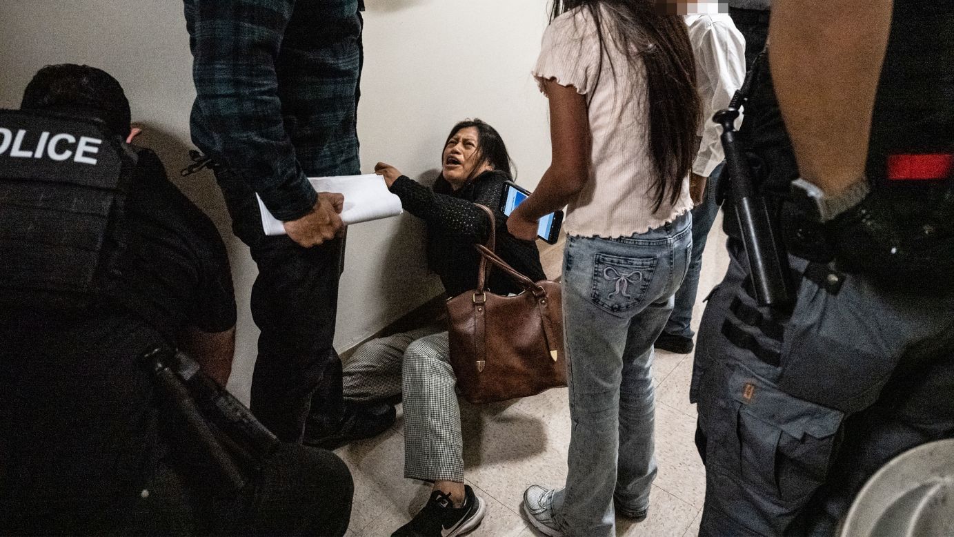 <em>Editor's note: A portion of this image was blurred to protect a child's privacy. </em>The wife of the detained man from Ecuador falls to the ground during an encounter with a federal agent.