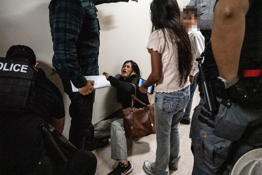 <em>Editor's note: A portion of this image was blurred to protect a child's privacy. </em>The wife of the detained man from Ecuador falls to the ground during an encounter with a federal agent.