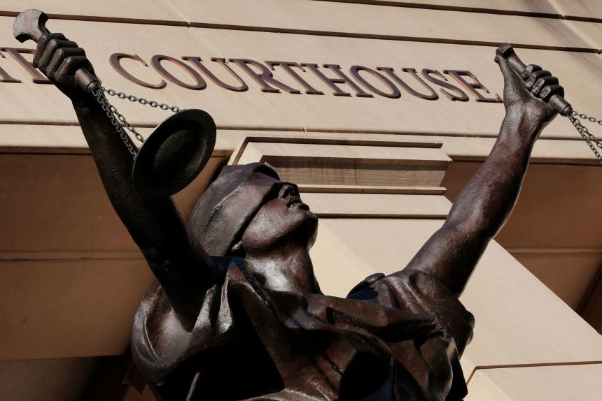 A statue of blindfolded Justice hovers over the entrance of the Bryan United States Courthouse in Alexandria, Virginia.