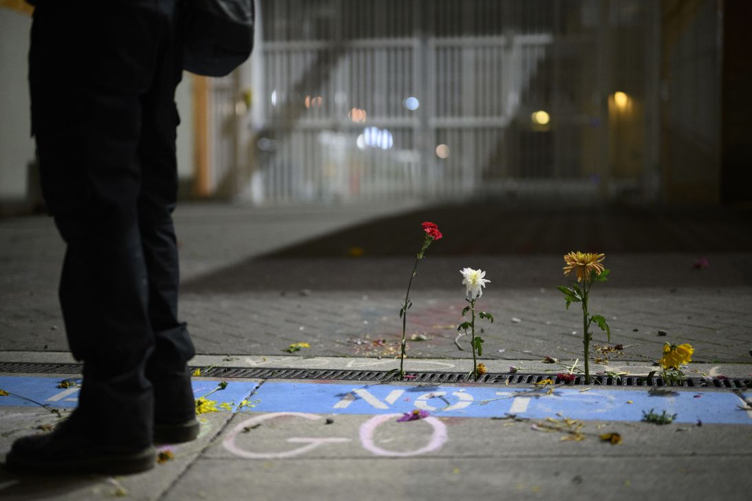 A protester stands next to flowers outside the Immigration and Customs Enforcement building on Saturday in Portland, Oregon.