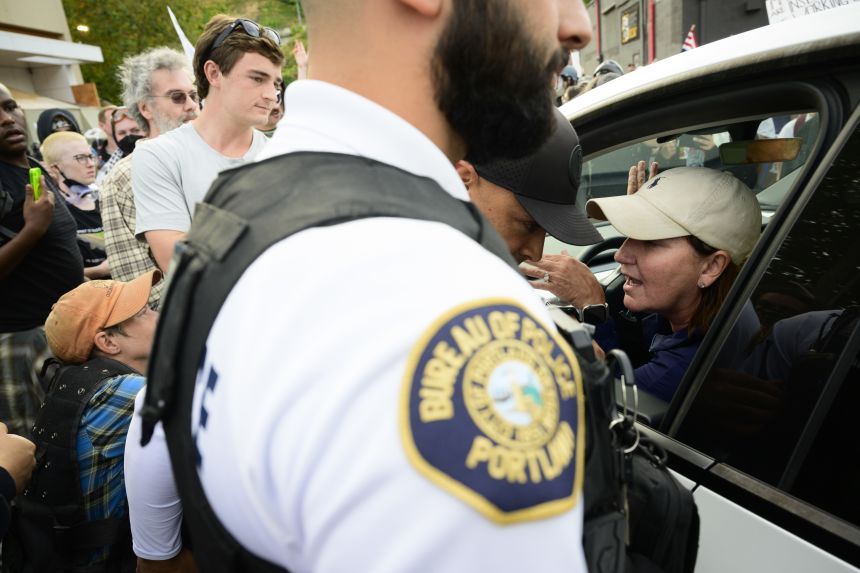 Protesters and Portland Police Officers engage a vehicle that drove into the crowd outside of the US Immigration and Customs Enforcement building in Portland, Oregon, on Sunday.