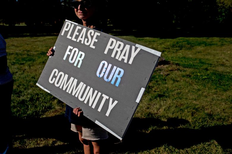 People hold signs Monday in support of the community after the shooting and fire at the Church of Jesus Christ of Latter-day Saints in Grand Blanc.