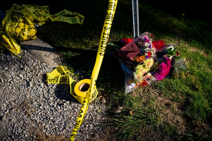 A makeshift memorial of flowers sits on the street next to police tape near the Church of Jesus Christ of Latter-day Saints on September 29 following a shooting and fire in Grand Blanc Township, Michigan. Four people were killed and eight wounded.