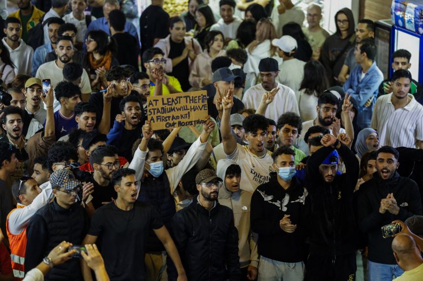 A Moroccan man holds a sign that reads, 