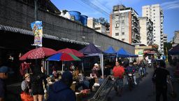 People sell groceries at stands outside the Quinta Crespo municipal market in Caracas on September 30, 2025. The Venezuelan currency closed September 2025 with a 71% drop against the dollar since January 2, to the distress of millions of families surviving the world's highest inflation, projected by the IMF at 254% by the end of 2025.