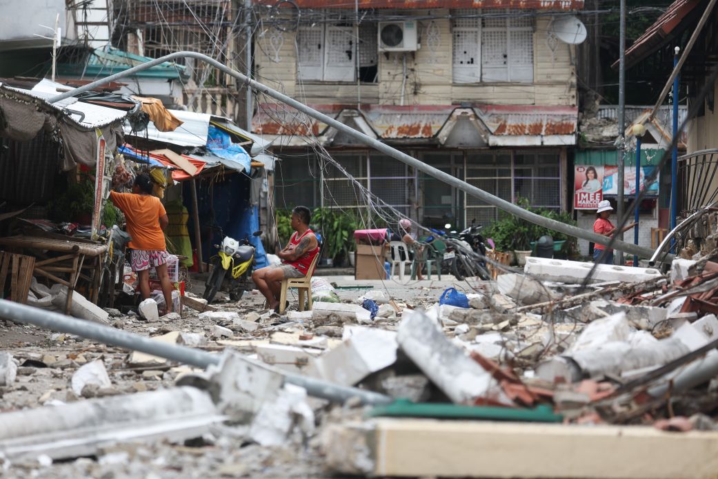 Bogo City residents stay on the streets near the debris of damaged buildings, amid frequent aftershocks, following a magnitude 6.9 earthquake in Cebu, Philippines, on October 1, 2025.