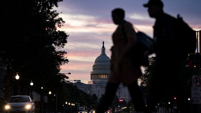 People cross Pennsylvania Avenue near the US Capitol in Washington DC, at dawn on October 1, 2025.