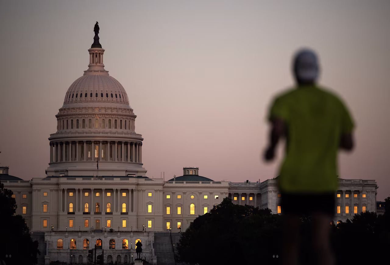 The sunset is reflected in the windows of the US Capitol as a man runs on the National Mall in Washington, DC, on Wednesday.
