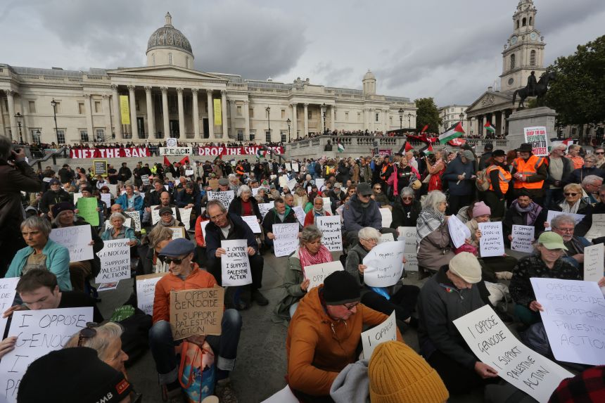 Pro-Palestinian activists hold signs during a demonstration in Trafalgar Square, central London, Saturday.
