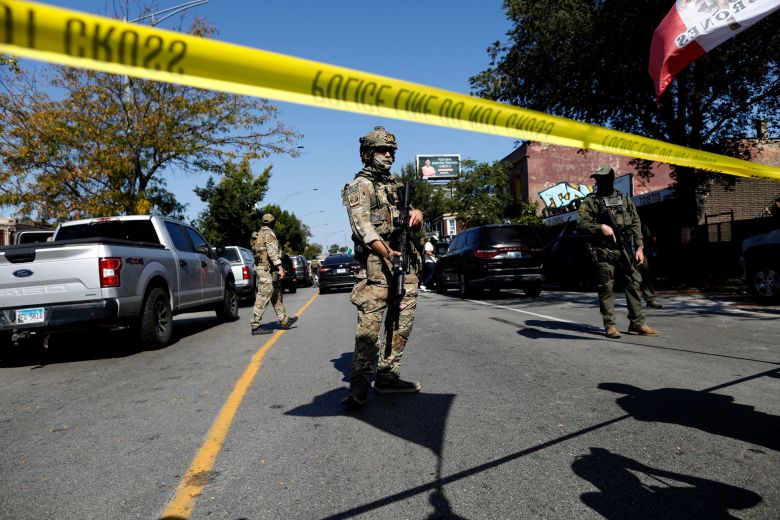 Masked US Customs and Border Protection (CBP) agents stand behind a police line as residents of Chicago's Brighton Park neighborhood confront law enforcement Saturday.