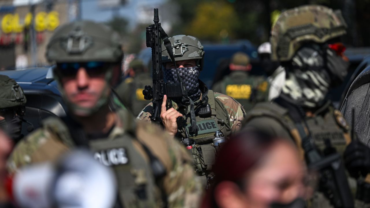 Federal Agents watch as demonstrators protest along Kedzie Avenue in the Brighton Park Neighborhood as Federal Agents were investigating a shooting on October 4, 2025 in Chicago, Illinois.