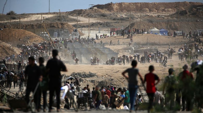 Palestinians carrying bags return from a food distribution point run by the Gaza Humanitarian Foundation near the Netsarim corridor in the central Gaza Strip on October 5, 2025.