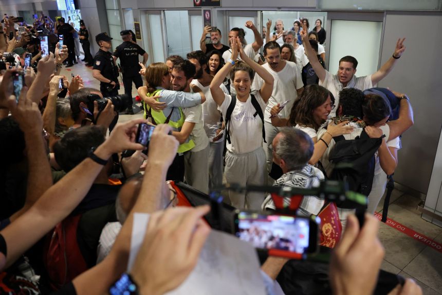 Flotilla participants, pictured wearing white shirts, who were sailing aboard vessels from the Global Sumud Flotilla applaud as they arrive at Madrid-Barajas Airport on October 5, 2025.