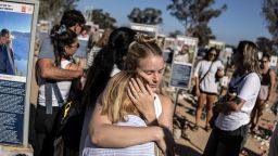 People embrace next to memorials of victims of the 2023 October 7 attacks at the Nova Festival grounds in Reim in southern Israel on the second anniversary of the attacks on October 7, 2025. Israel marks the second anniversary of the October 7, 2023 attack as Hamas and Israeli negotiators hold indirect talks to end the two-year war in Gaza under a US-proposed peace plan. Two years prior to the day, at the close of the Jewish festival of Sukkot, Hamas-led militants launched a massive assault on Israel, making it the deadliest day in the country's history. (Photo by JOHN WESSELS / AFP) (Photo by JOHN WESSELS/AFP via Getty Images)          