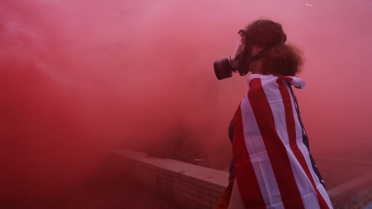 A protester stands in the haze from a smoke grenade outside of a downtown U.S. Immigration and Customs Enforcement (ICE) facility in Portland, Oregon on October 4, 2025.