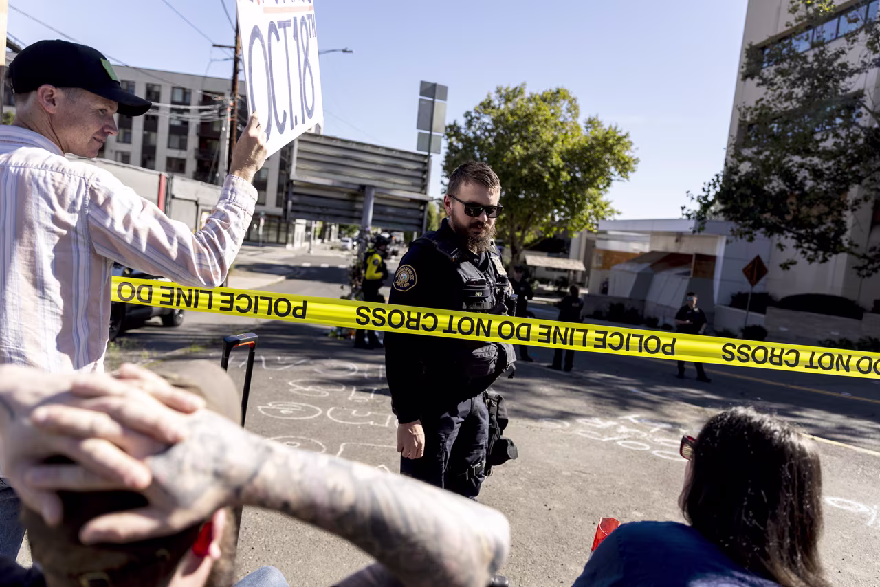 A police officer with the Portland Police Bureau talks to a group of protesters waiting at the United States Immigration and Customs Enforcement facility in Portland, on Tuesday.
