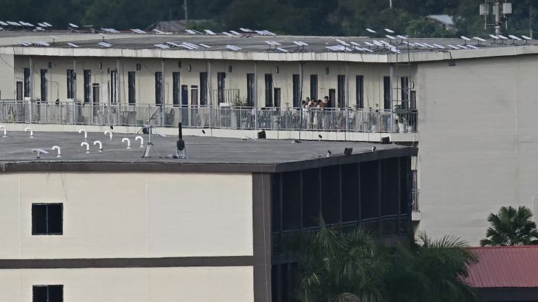 People on a balcony of a building with what appears to be Starlink satellite dishes on the roof in the KK Park complex in Myanmar's eastern Myawaddy township, as pictured from Mae Sot district in Thailand's border province of Tak, on September 17, 2025.