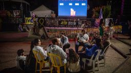 People sit and talk in front of a clock counting the days the hostages have been in captivity at Hostages Square in Tel Aviv, Israel on Monday.