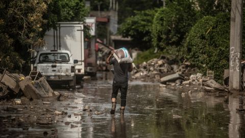 A man wades through mud after severe flooding hit the town of Poza Rica, in Veracruz state, Mexico, on October 14, 2025. Rescuers scrambled Monday to reach people cut off by devastating floods that have claimed 64 lives in central and eastern Mexico, with another 65 reported missing. (Photo by Hector QUINTANAR / AFP) (Photo by HECTOR QUINTANAR/AFP via Getty Images)          