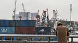 A man stands as a cargo ship carrying containers sails into a dock at a container terminal in Shanghai, on October 17, 2025.