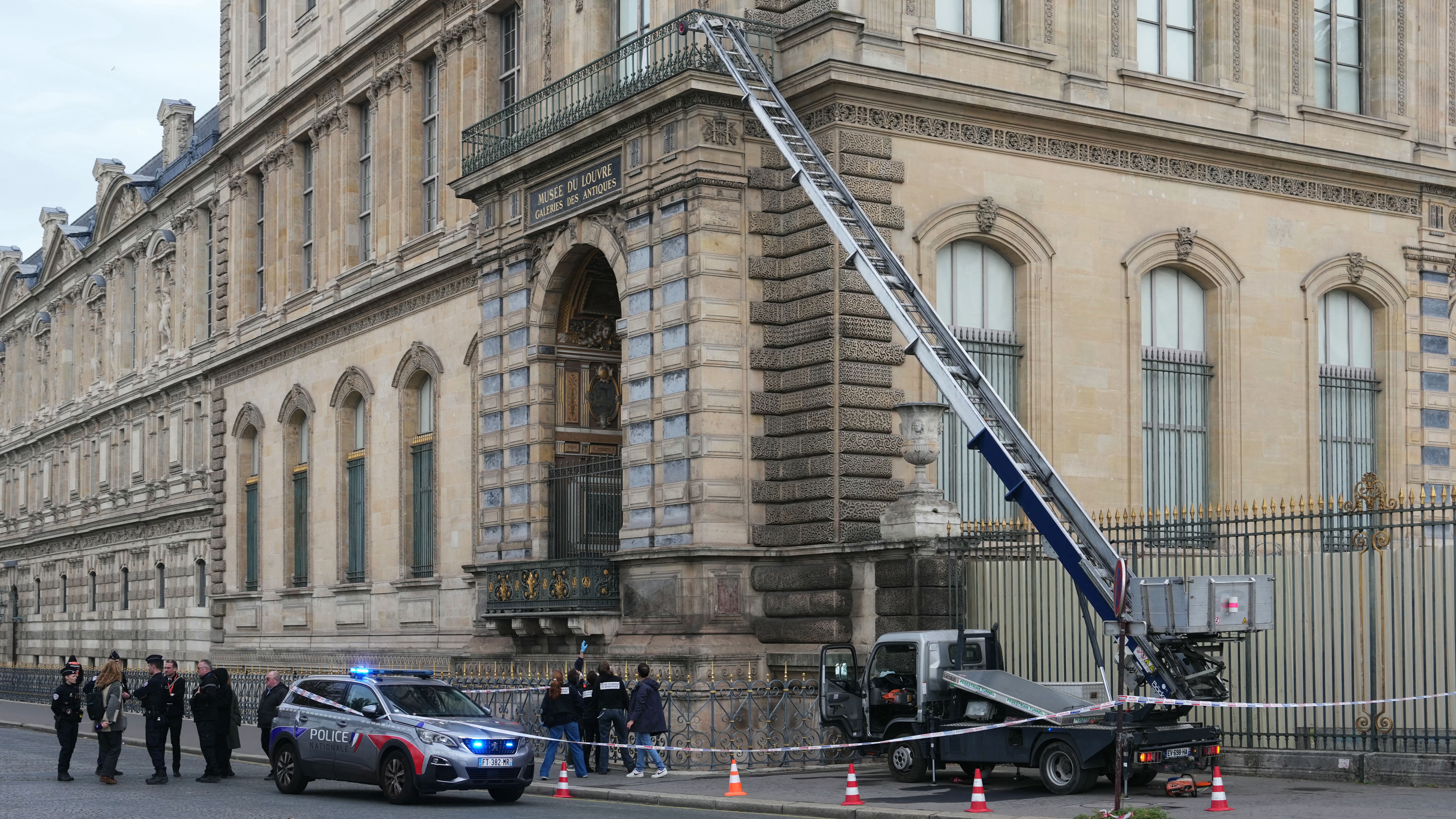 French police officers stand next to a furniture elevator used by robbers to enter the Louvre Museum, on Quai Francois Mitterrand, in Paris, on October 19, 2025.