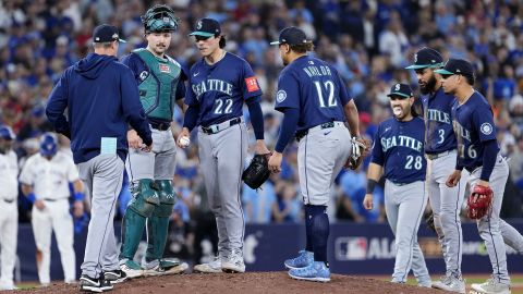 TORONTO, ONTARIO - OCTOBER 20: Manager Dan Wilson #6 of the Seattle Mariners takes the ball from Bryan Woo #22 during a pitching change in the seventh inning against the Toronto Blue Jays in game seven of the American League Championship Series at the Rogers Centre on October 20, 2025 in Toronto, Ontario.  (Photo by Mark Blinch/Getty Images)