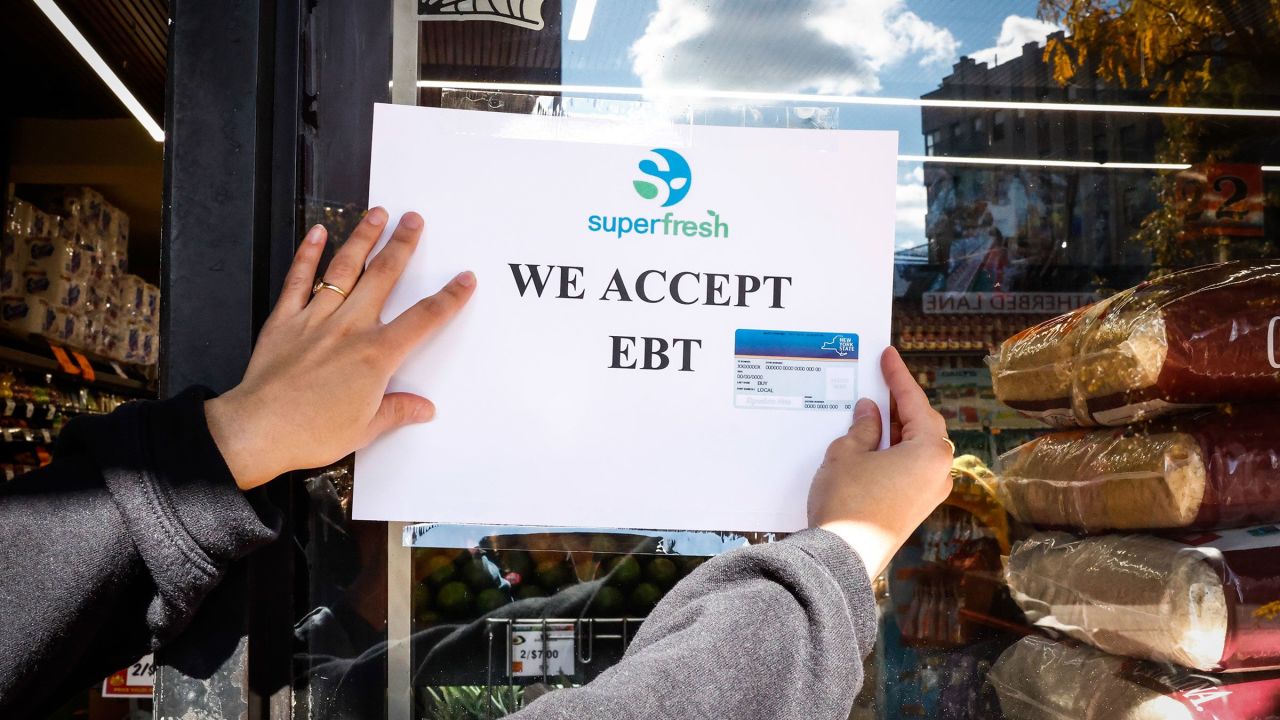 A worker places an Electronic Benefit Transfer (EBT) sign outside a grocery store in the Bronx borough of New York, US, on Friday, Oct. 24, 2025. The political firestorm over the looming cutoff in food-aid funding intensified Thursday as lawmakers from both parties sounded alarms and some states warned retailers of its consequences. Photographer: Kena Betancur/Bloomberg via Getty Images